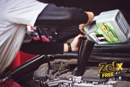 man refilling motor oil on car engine bay