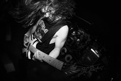A musician plays guitar with long, wild hair.