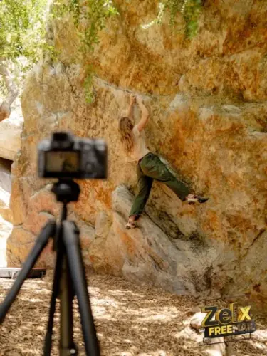 A man is climbing up a rock with a camera