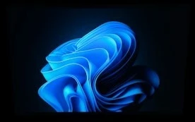 A laptop screen displaying a glowing blue abstract wave pattern in a dark room